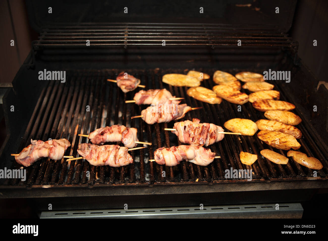 Grillen Speck eingewickelt Hähnchen und Kartoffeln auf dem Grill in der Nacht Stockfoto