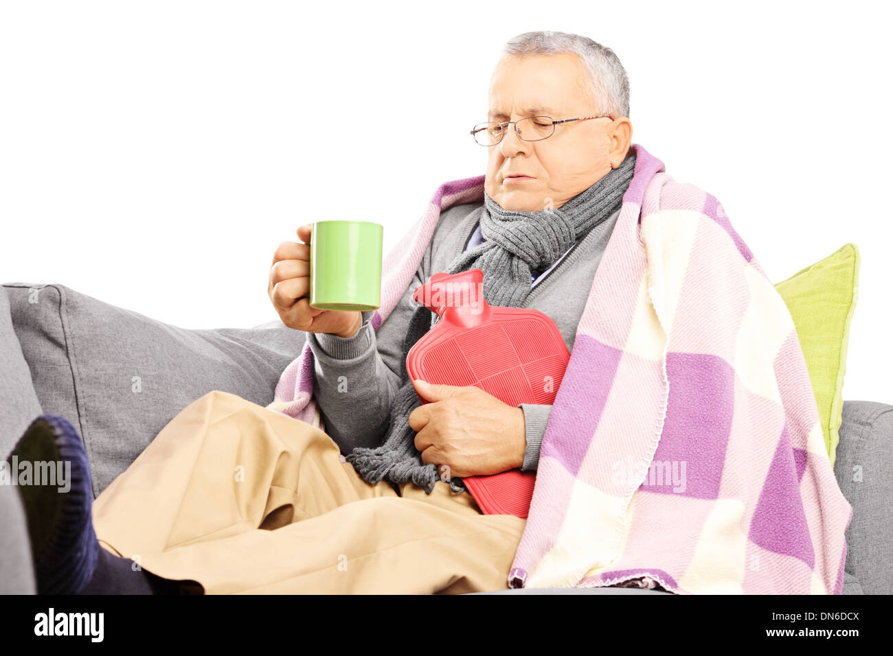 Kranker Mann mittlerer Alter auf einem Sofa bedeckt mit Decke trinken heißen Tee Stockfoto