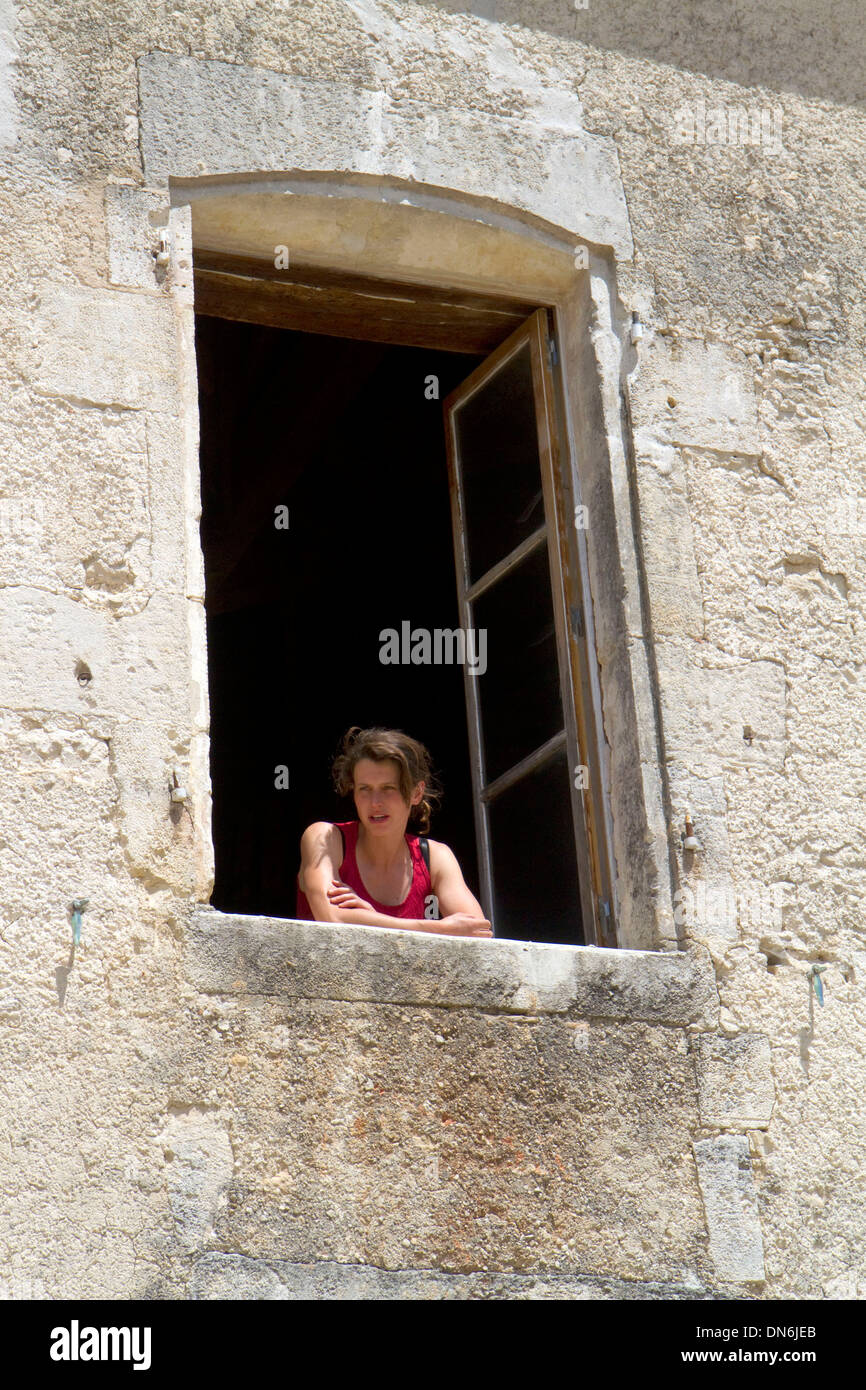 Junge Frau schaut aus dem Fenster eines französischen Bauernhaus in der Nähe von Angoulême im Südwesten Frankreichs. Stockfoto