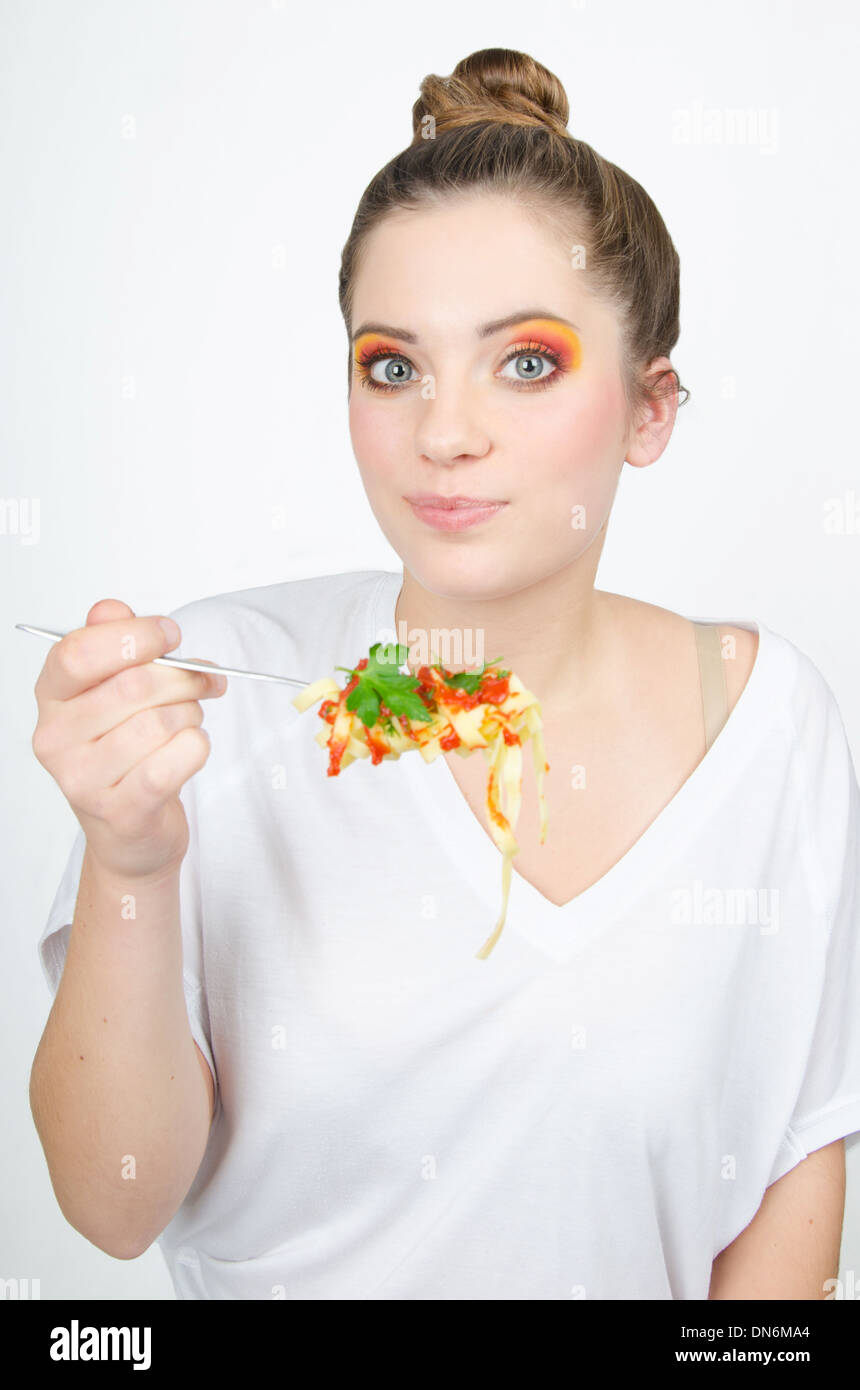 Frau in einem bunten Make-up und eingewickelt auf Gabel Spaghetti Stockfoto