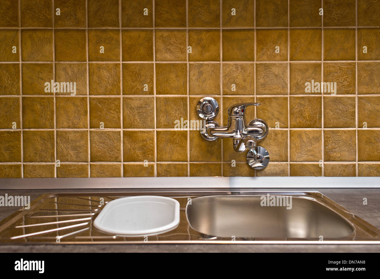 Edelstahl Küchenarmatur und Waschbecken Keramik gefliesten Wand Stockfoto