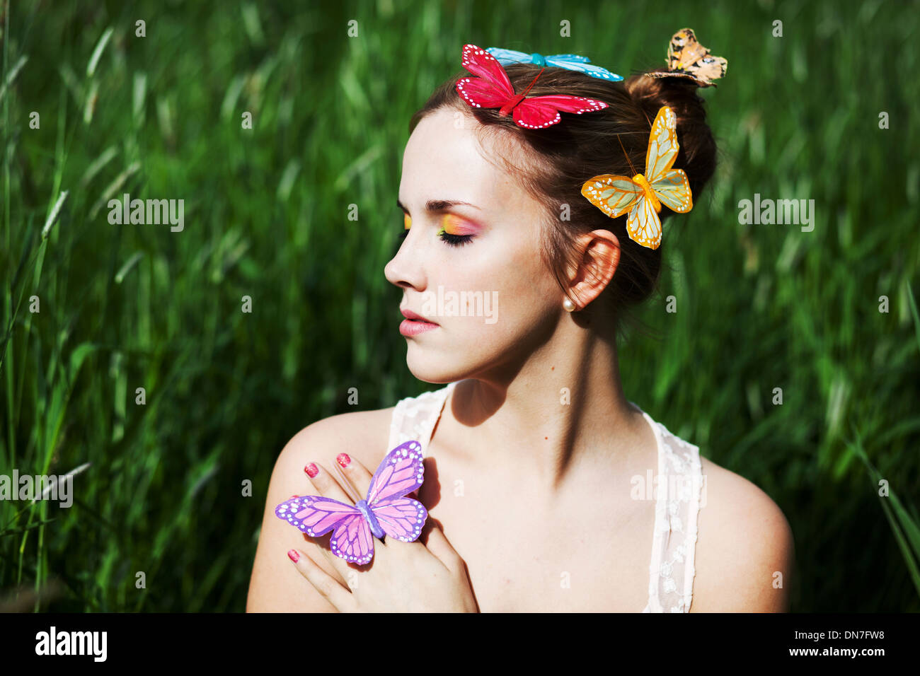 Junge Frau mit geschlossenen Augen und künstliche Schmetterlinge Stockfoto