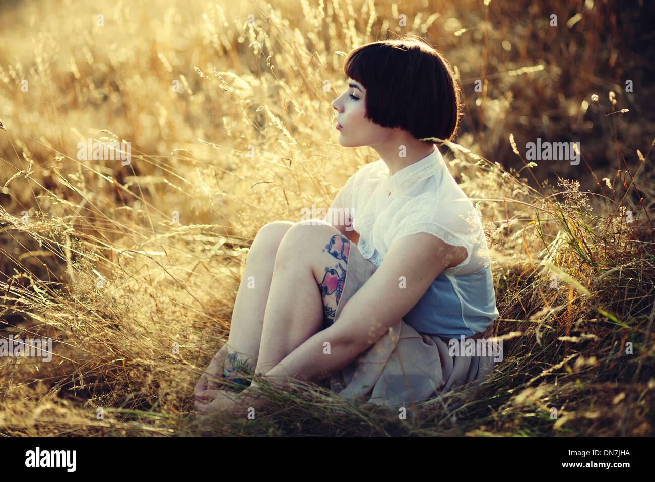 Junge Frau sitzt auf einer Wiese, Porträt Stockfoto