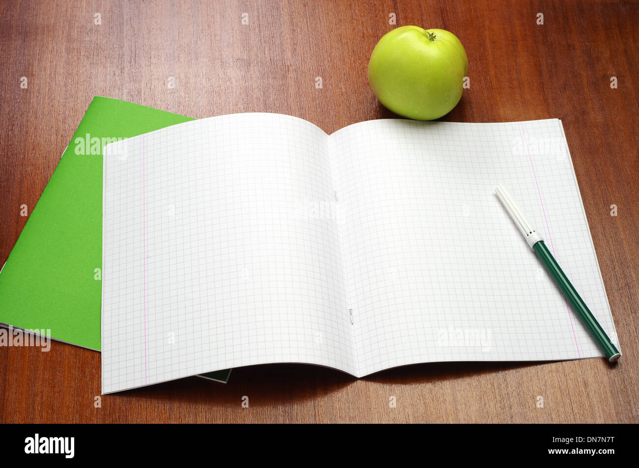 Schulheft, Filzstifte und grüner Apfel auf Tisch eröffnet Stockfoto