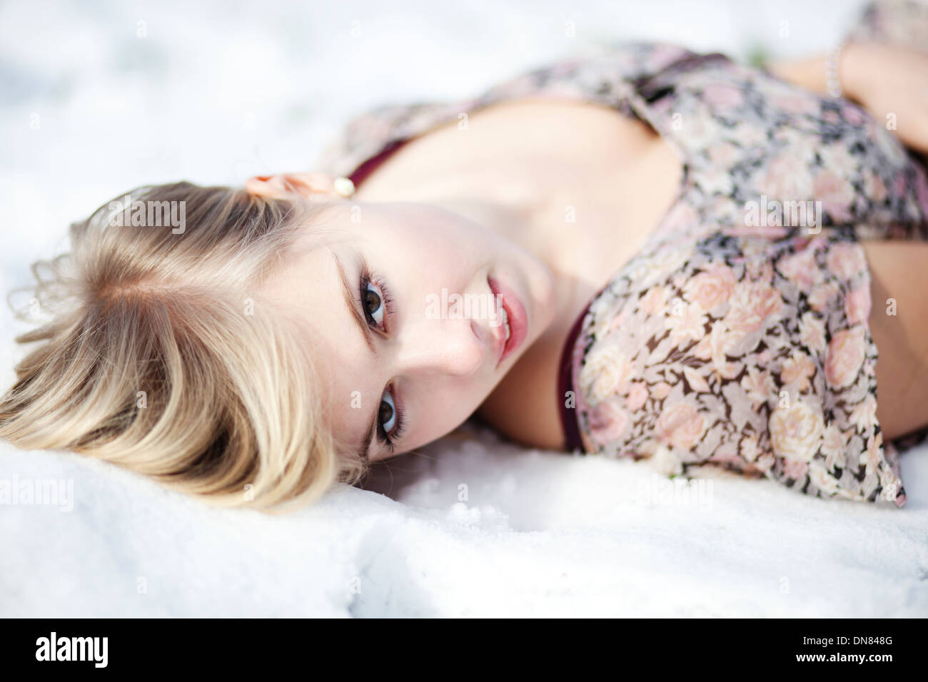 Junge Frau liegt im Schnee, Porträt Stockfoto