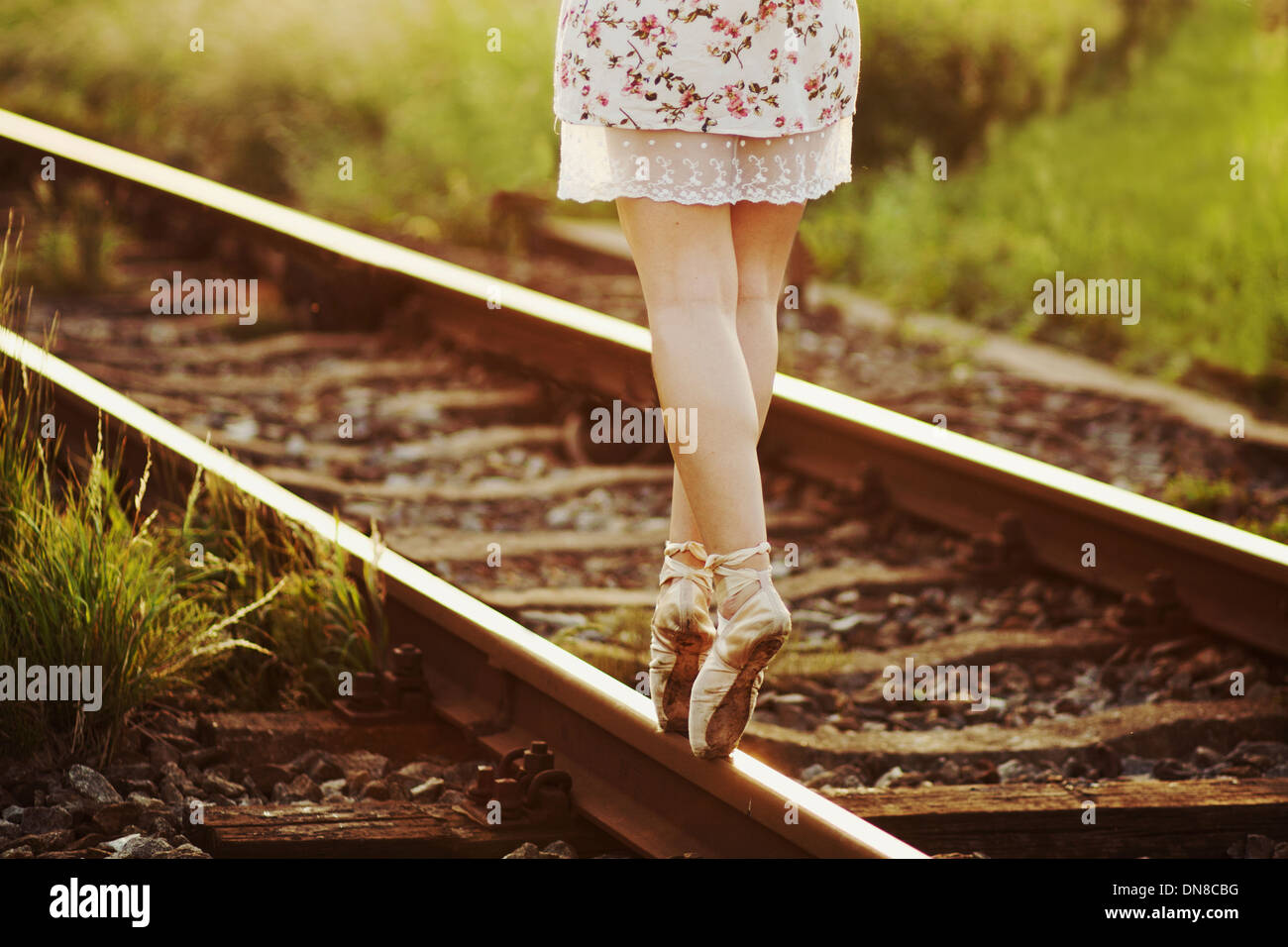 Junge Frau im Kleid, balancieren auf einem Gleis Stockfoto