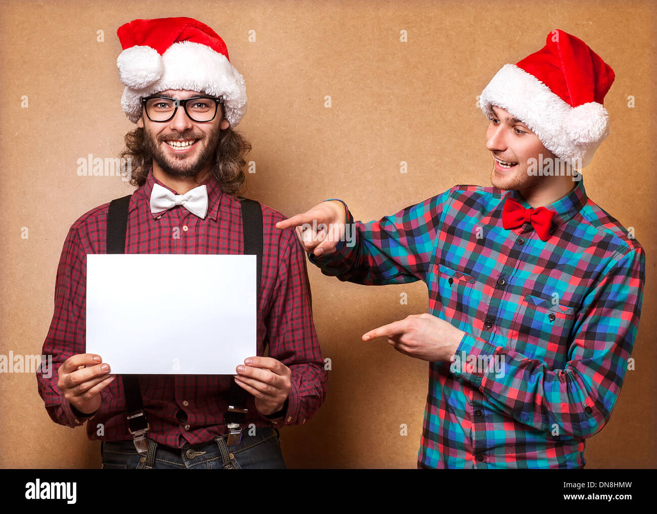 Weihnachten, Weihnachten, Menschen, Werbung, Verkauf Konzept - zwei glücklich in Helfer Weihnachtsmütze mit leeren weißen Tafel. Hipster-Stil. Stockfoto