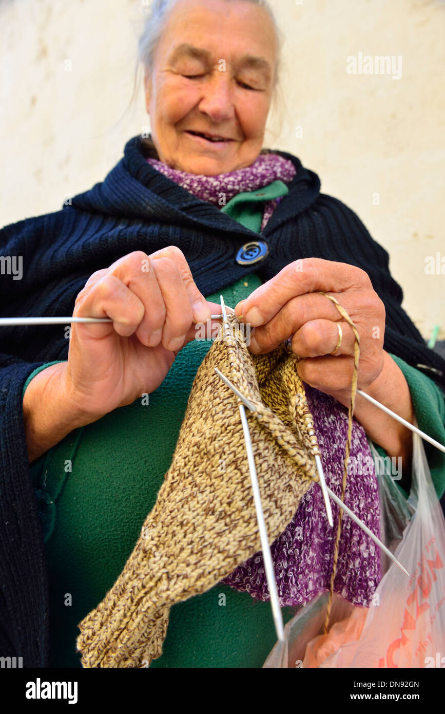 Alte Dame strickt auf Šibenik dem Marktplatz in Kroatien. Die Kleidungsstücke stehen dann zum Verkauf Stockfoto