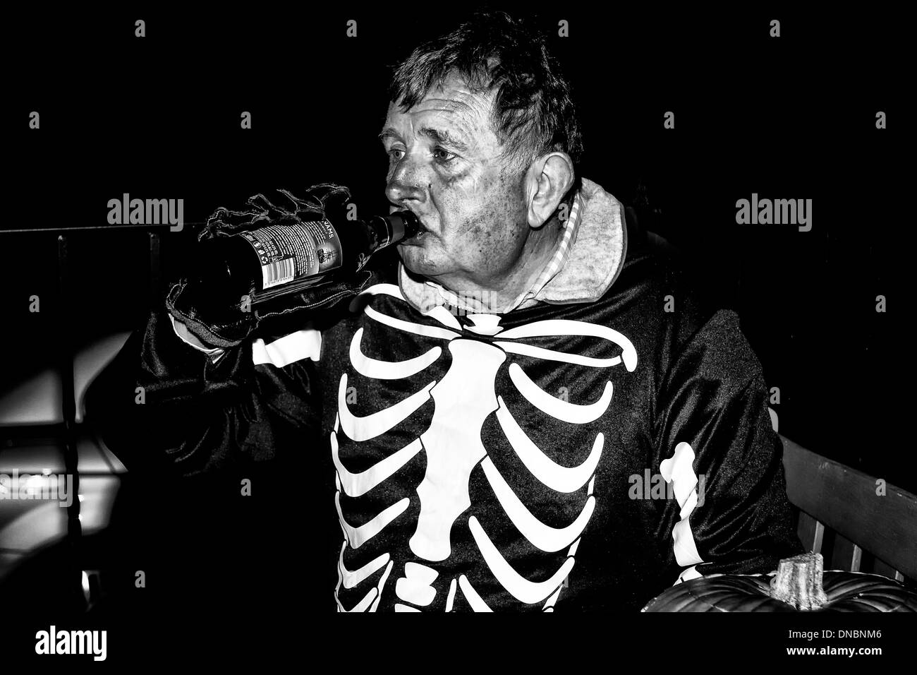 Mann in Halloween Skelett Kostüm Bier aus der Flasche trinken Stockfoto