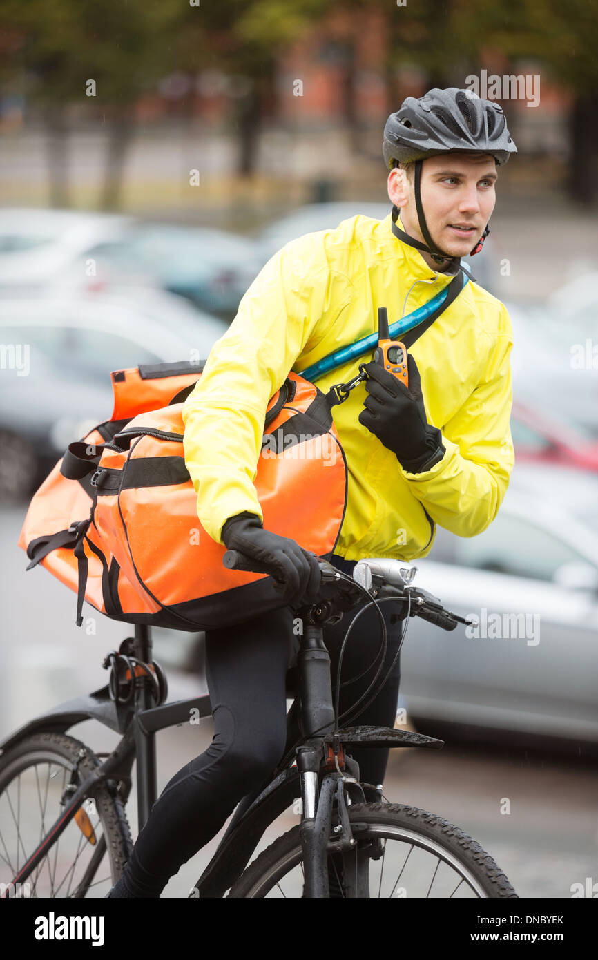 Männliche Radfahrer mit Kuriertasche mit Walkie-Talkie Stockfoto