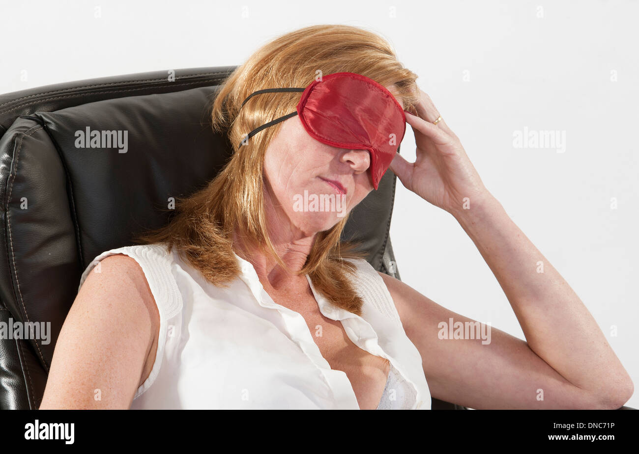 Frau trägt Augenmaske schlafen in einem Bürostuhl Stockfoto