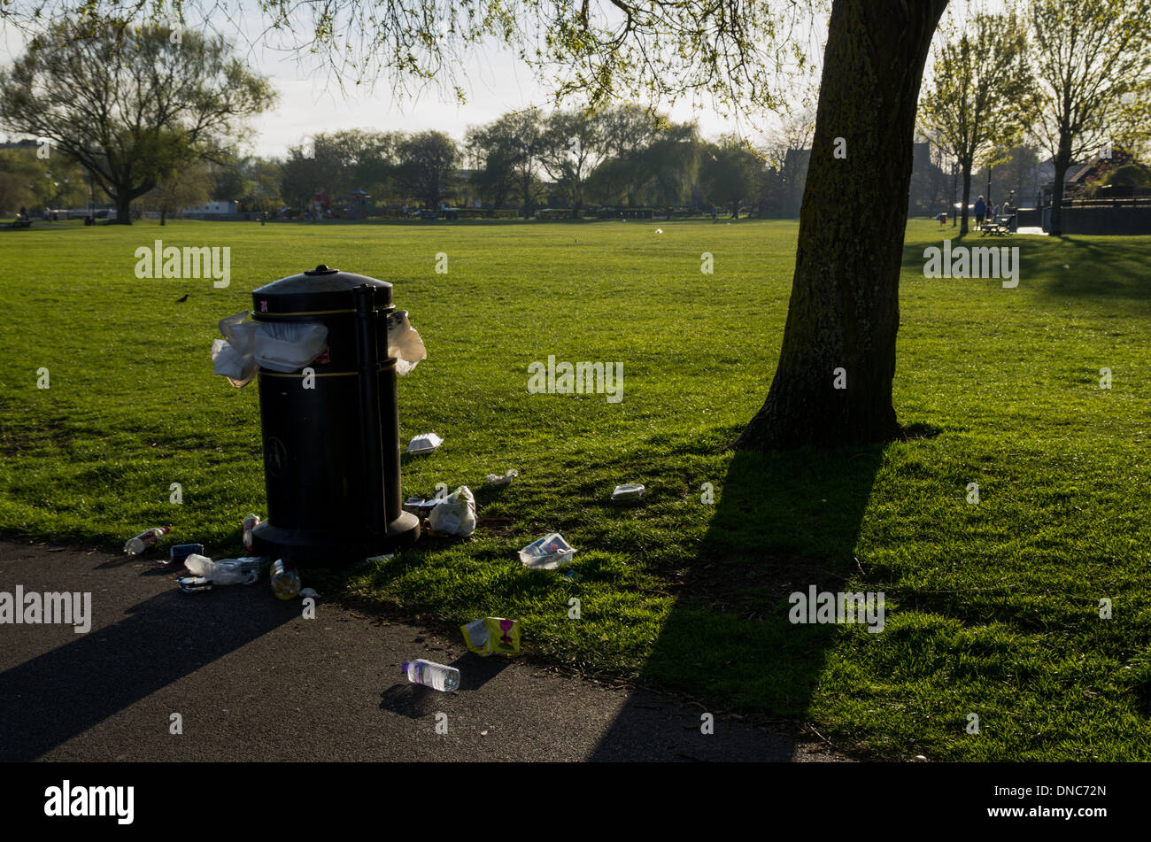 Eine überfüllte Mülleimer in einem Park an einem sonnigen Tag mit Müll verstreut. Stockfoto