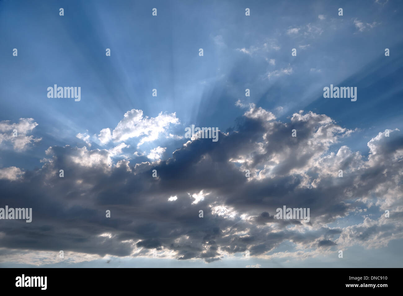 Die Sonnenstrahlen, die durch dunkle Wolken Stockfoto