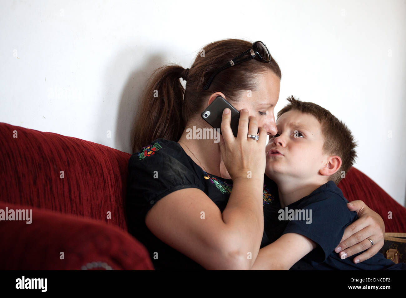 Mutter versucht, am Telefon zu sprechen, beim neigen zu kleinen Sohn. Lodz Polen Stockfoto