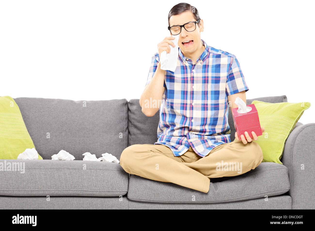 Traurige Kerl auf einem Sofa sitzt und wischte sich die Augen vom Weinen Stockfoto