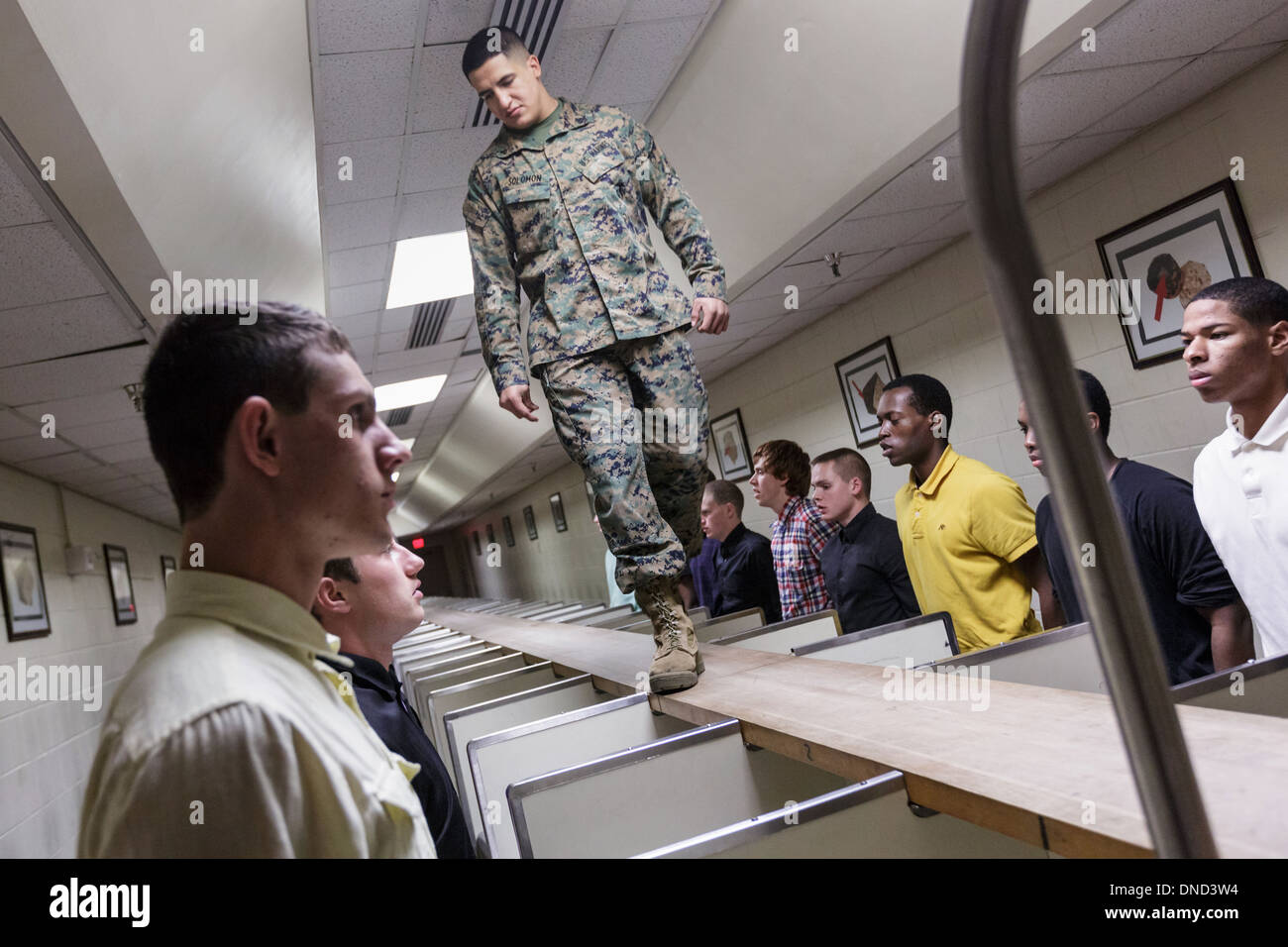 Ein US-Marine wacht über neu angekommenen Rekruten, wie sie ihre Ausrüstung bei Empfang im Marine Corps zu rekrutieren Depot Parris Island ab 13 Wochen von Boot Camp 9. Dezember 2013 in Port Royal, South Carolina ausgestellt werden. Die Marines trainieren jährlich etwa 17.000 Rekruten auf Parris Island. Stockfoto