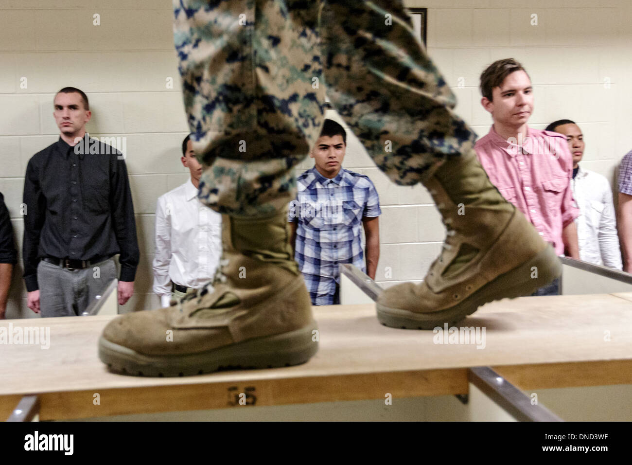 Ein US-Marine wacht über neu angekommenen Rekruten, wie sie ihre Ausrüstung bei Empfang im Marine Corps zu rekrutieren Depot Parris Island ab 13 Wochen von Boot Camp 9. Dezember 2013 in Port Royal, South Carolina ausgestellt werden. Die Marines trainieren jährlich etwa 17.000 Rekruten auf Parris Island. Stockfoto