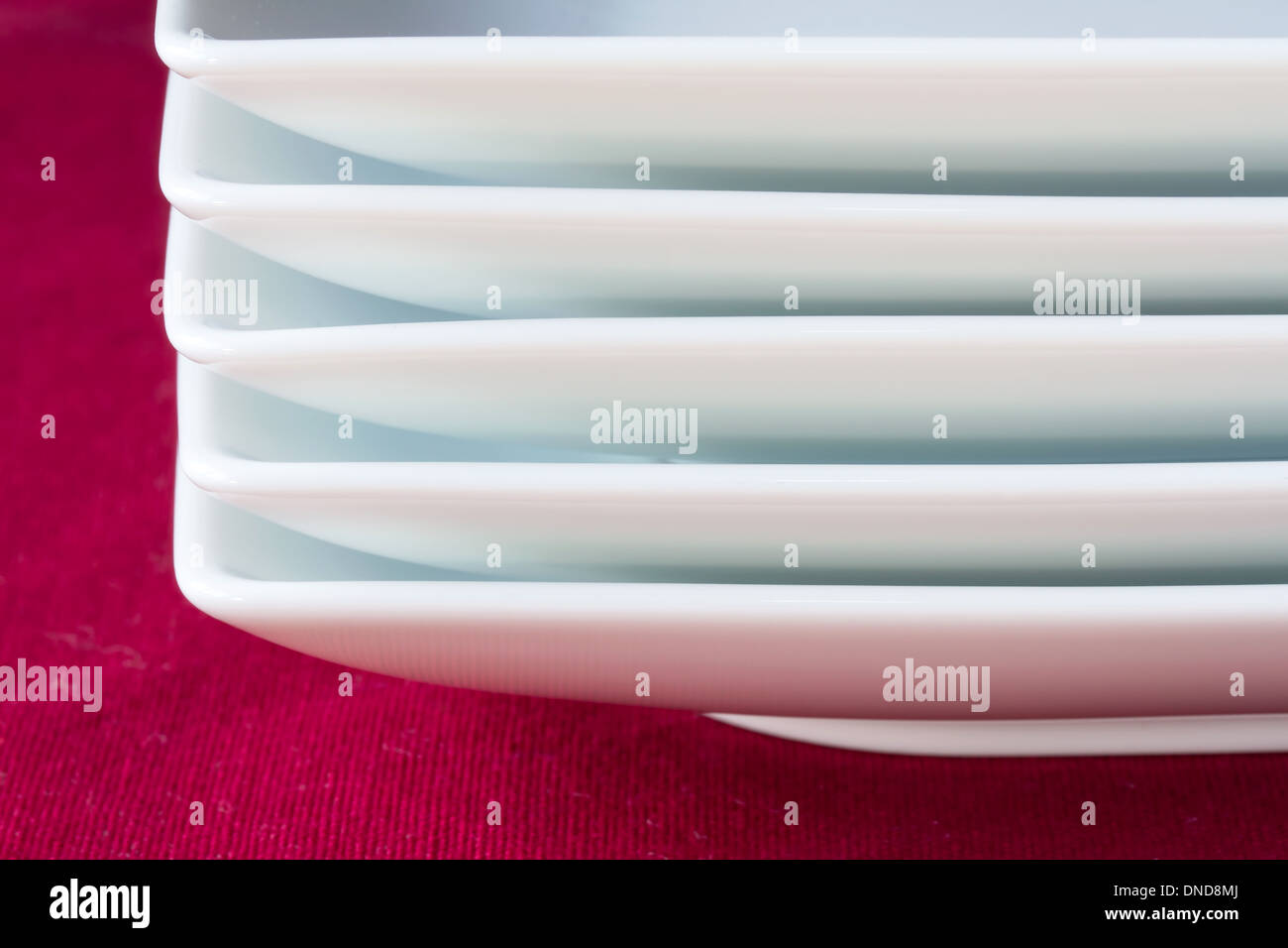 Stapel von weißen Platten auf roten Tischdecke Stockfoto