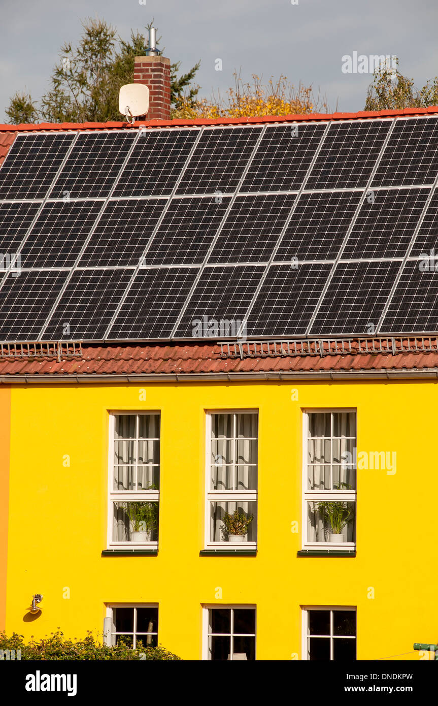 Solaranlage auf Privathaus mit roten Dachziegeln und gelben Wänden installiert. Stockfoto