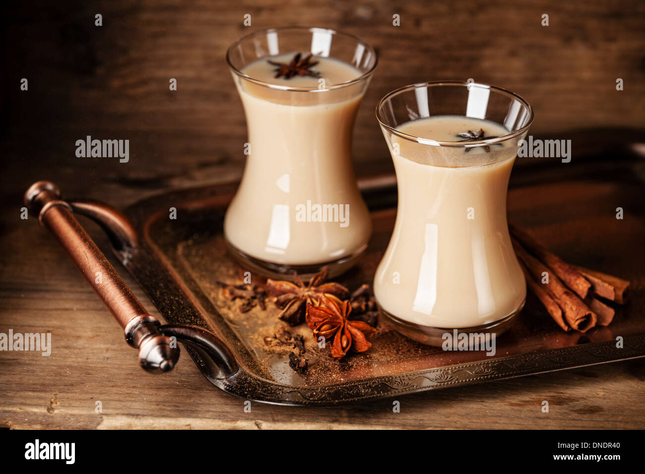 Heißen Tee mit Milch und Gewürzen auf dunklem Hintergrund Stockfoto