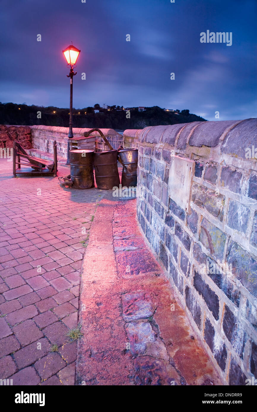 Der alte Stein Hafenmauer und Docks in Tenby, Pembrokeshire, werden durch die alte Straßenlaterne in der Nacht beleuchtet. Stockfoto