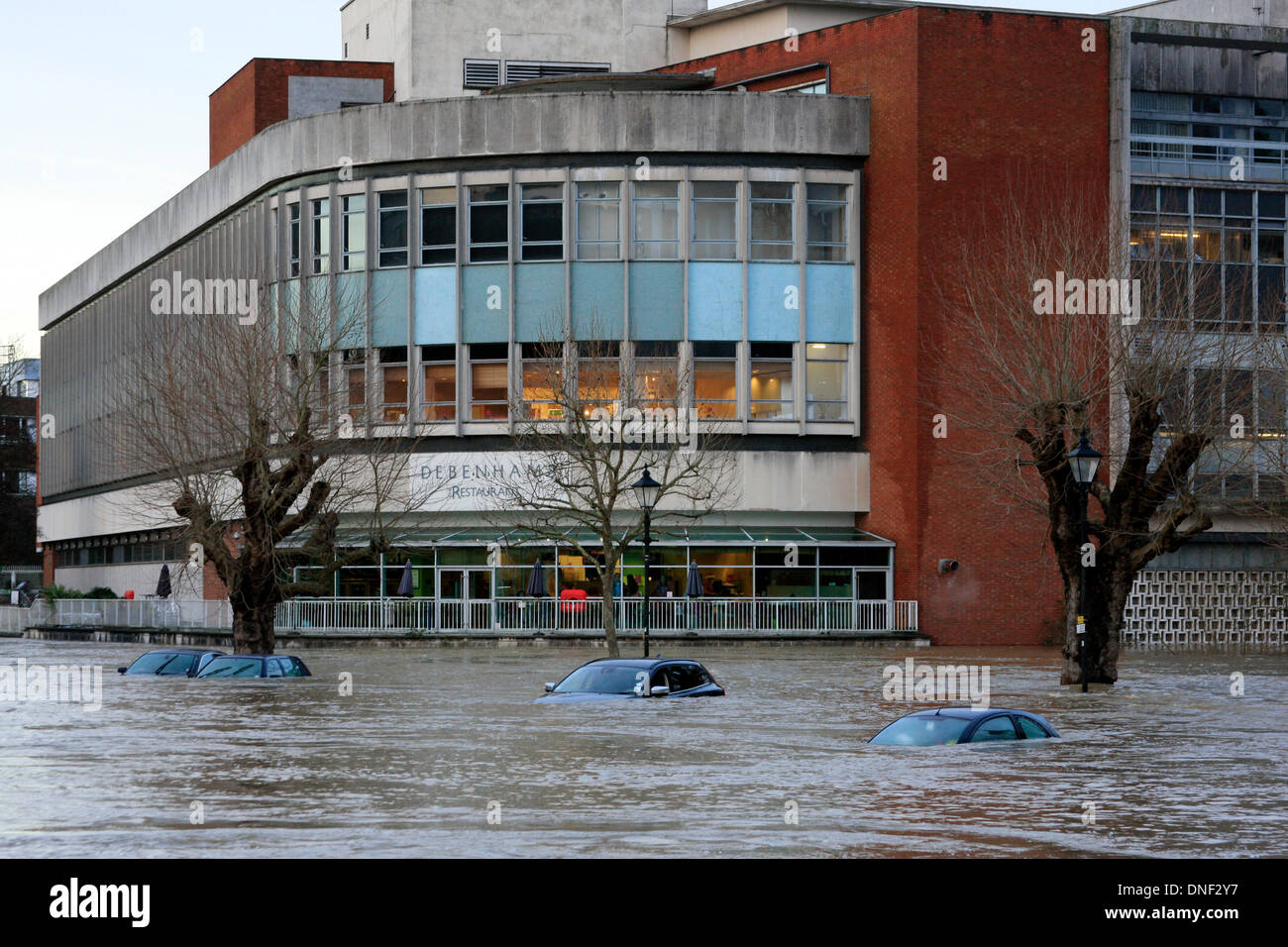 Guildford, Surrey, UK 24. Dezember 2013. Steigenden Flutwasser aus dem Fluss Wey umhüllt Autos im Millmead Parkplatz mit dem Kaufhaus Debenhams im Hintergrund. Die Überschwemmung ist durch starke Regenfälle in den letzten 24 Stunden entstanden. Bildnachweis: Bruce McGowan/Alamy Live-Nachrichten Stockfoto