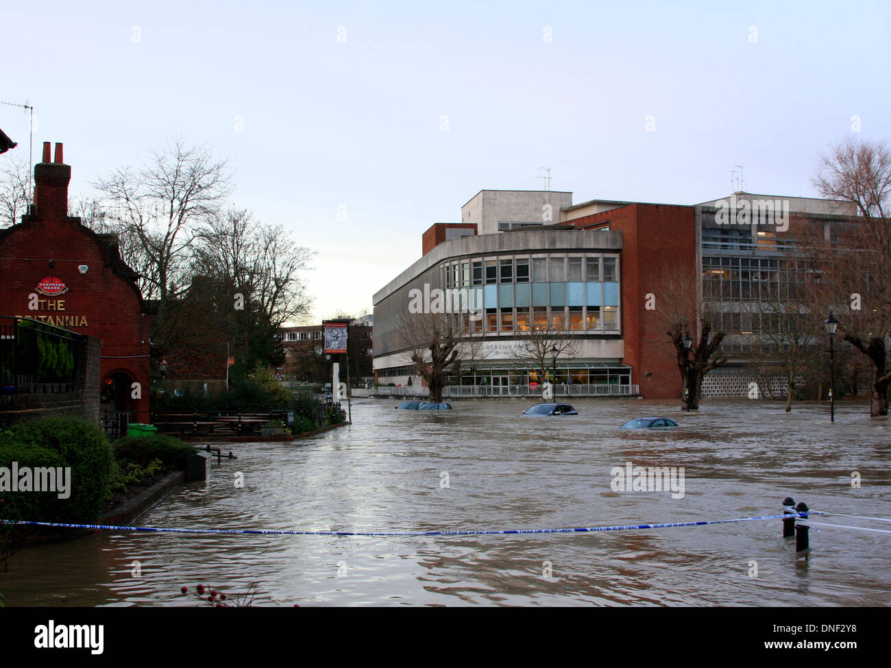 Guildford, Surrey, UK 24. Dezember 2013. Steigenden Flutwasser aus dem Fluss Wey umhüllt Autos im Millmead Parkplatz mit dem Kaufhaus Debenhams im Hintergrund. Die Überschwemmung ist durch starke Regenfälle in den letzten 24 Stunden entstanden. Bildnachweis: Bruce McGowan/Alamy Live-Nachrichten Stockfoto