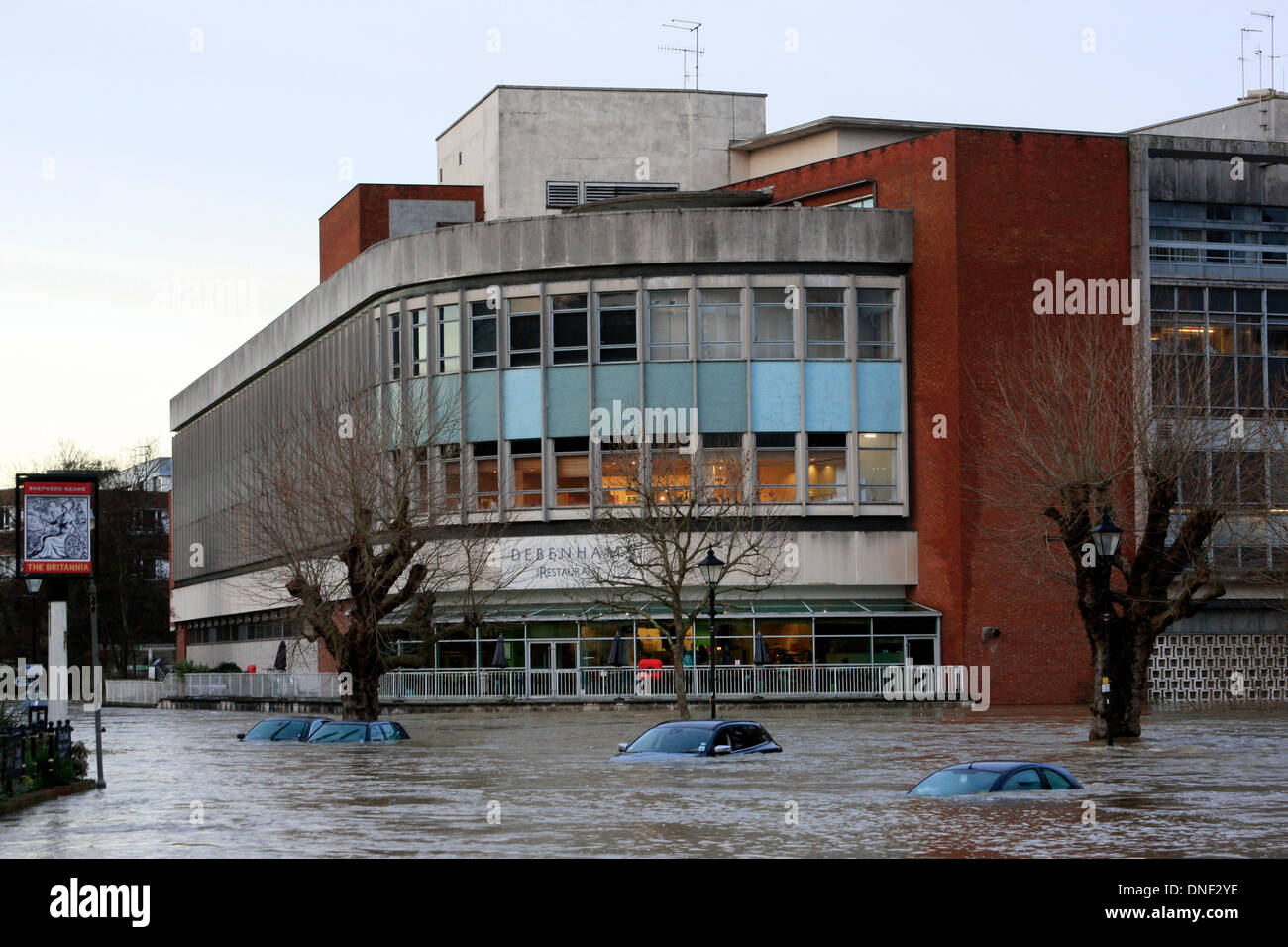 Guildford, Surrey, UK 24. Dezember 2013. Steigenden Flutwasser aus dem Fluss Wey umhüllt Autos im Millmead Parkplatz mit dem Kaufhaus Debenhams im Hintergrund. Die Überschwemmung ist durch starke Regenfälle in den letzten 24 Stunden entstanden. Bildnachweis: Bruce McGowan/Alamy Live-Nachrichten Stockfoto