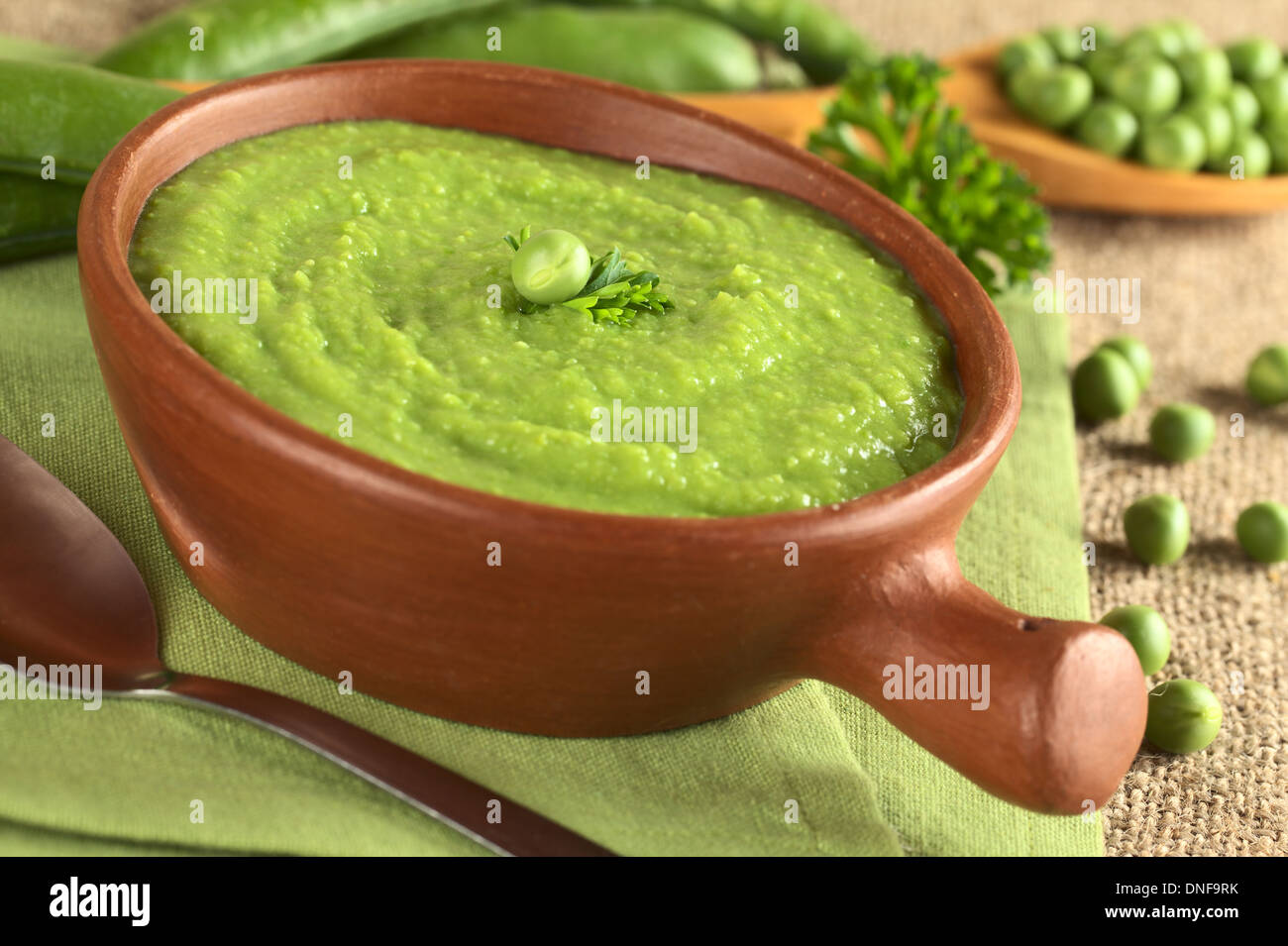 Frische grüne Erbsensuppe in rustikalen Schüssel (selektiven Fokus, Fokus auf der Erbse und die Petersilie-Blatt in der Mitte der Suppe) Stockfoto