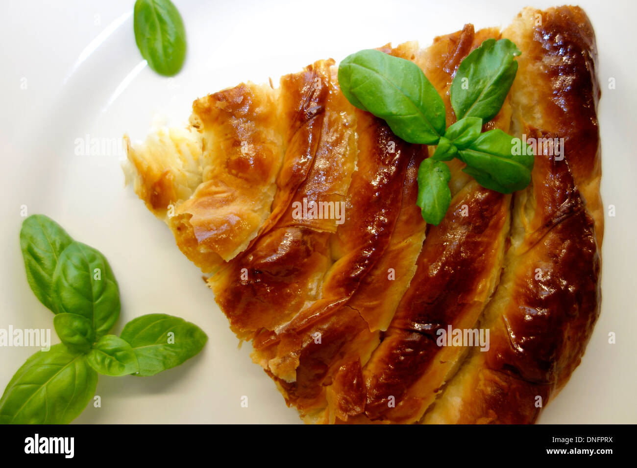 Ein Stück des traditionellen Wirbel förmigen Balkan Pie auf dem Silbertablett serviert und mit frischem Basilikum garniert. Stockfoto