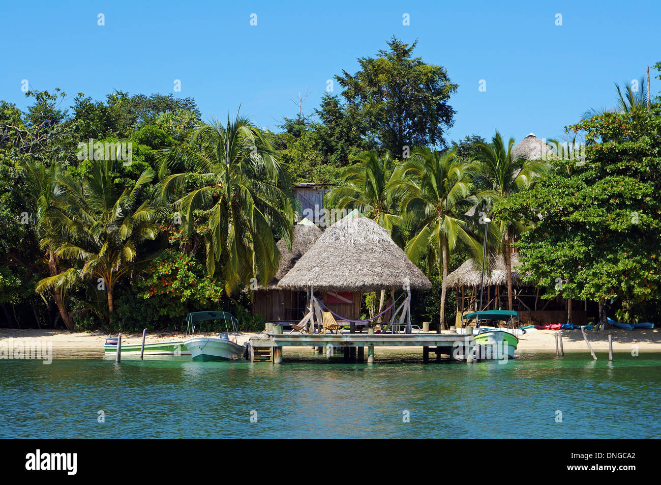 Am Strand Eco resort mit strohgedeckten Hütte über Wasser und tropische Vegetation, Karibik, Bocas del Toro, Panama Stockfoto