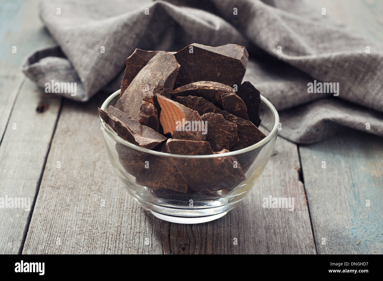 Schokoladenstücke in Glasschüssel auf hölzernen Hintergrund Stockfoto