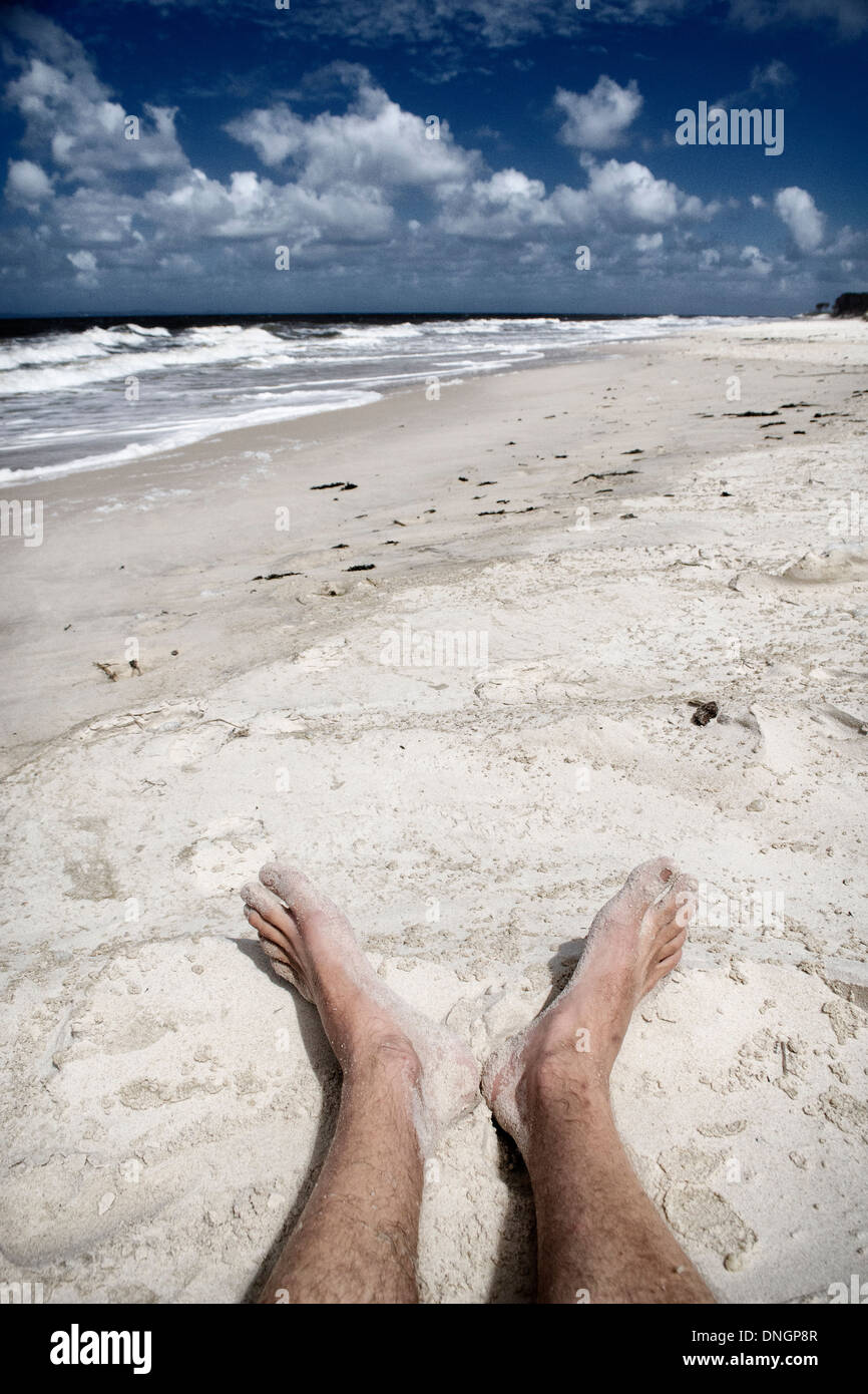 Behaarte männliche Füße an einem sonnigen Strand Stockfoto