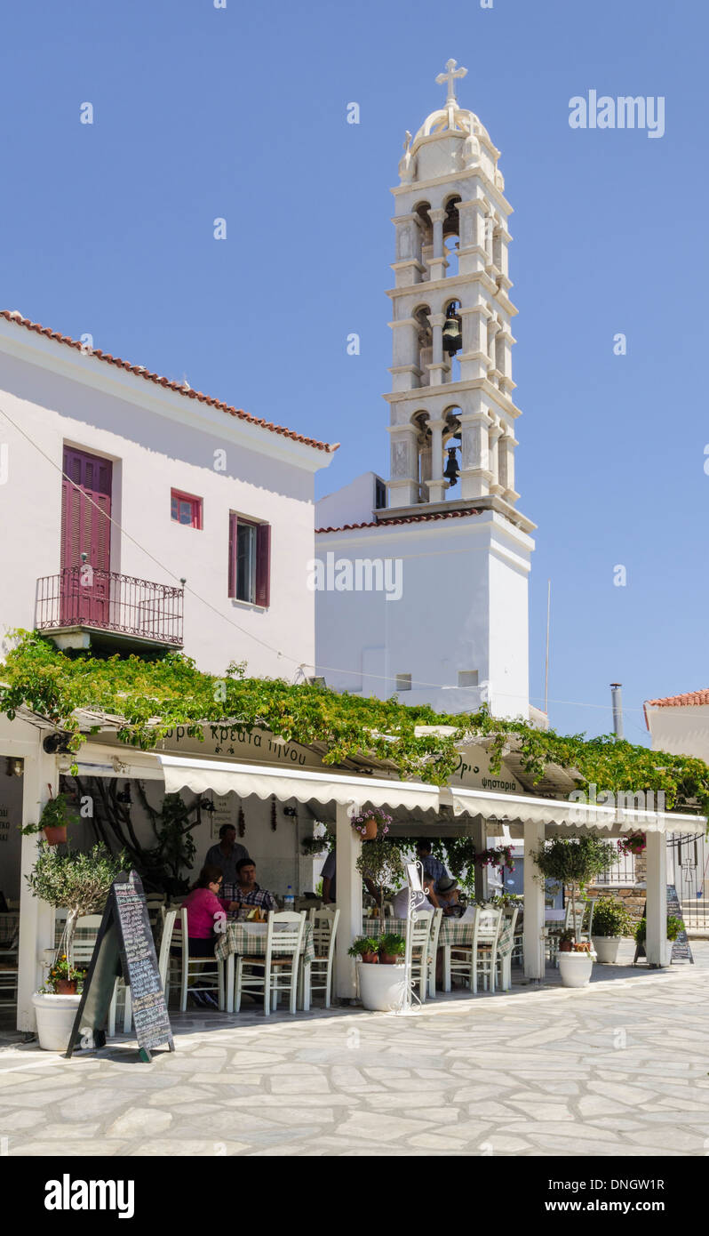 Glockenturm der Kirche hinter einer griechischen Taverne, Tinos-Stadt, Insel Tinos, Kykladen, Griechenland Stockfoto