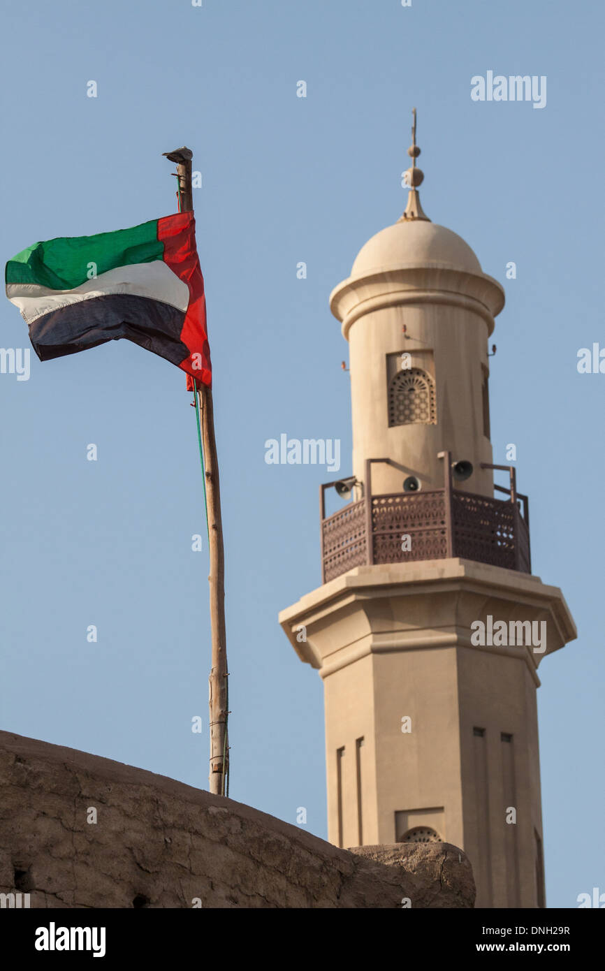 VEREINIGTE ARABISCHE EMIRATE FAHNE IN DEN WIND MIT DEM MINARETT DER GROßEN MOSCHEE VON DUBAI IM HINTERGRUND SCHWEBEN, VEREINIGTE DUBAI, ARABISCHE EMIRATE, NAHOST Stockfoto