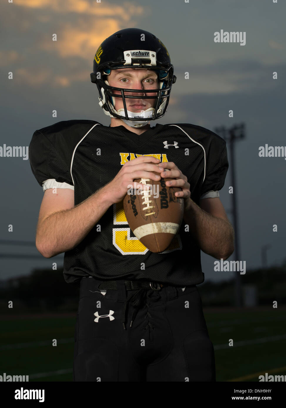 American High School Football-Spieler in Uniform mit Helm und Fußball. Stockfoto