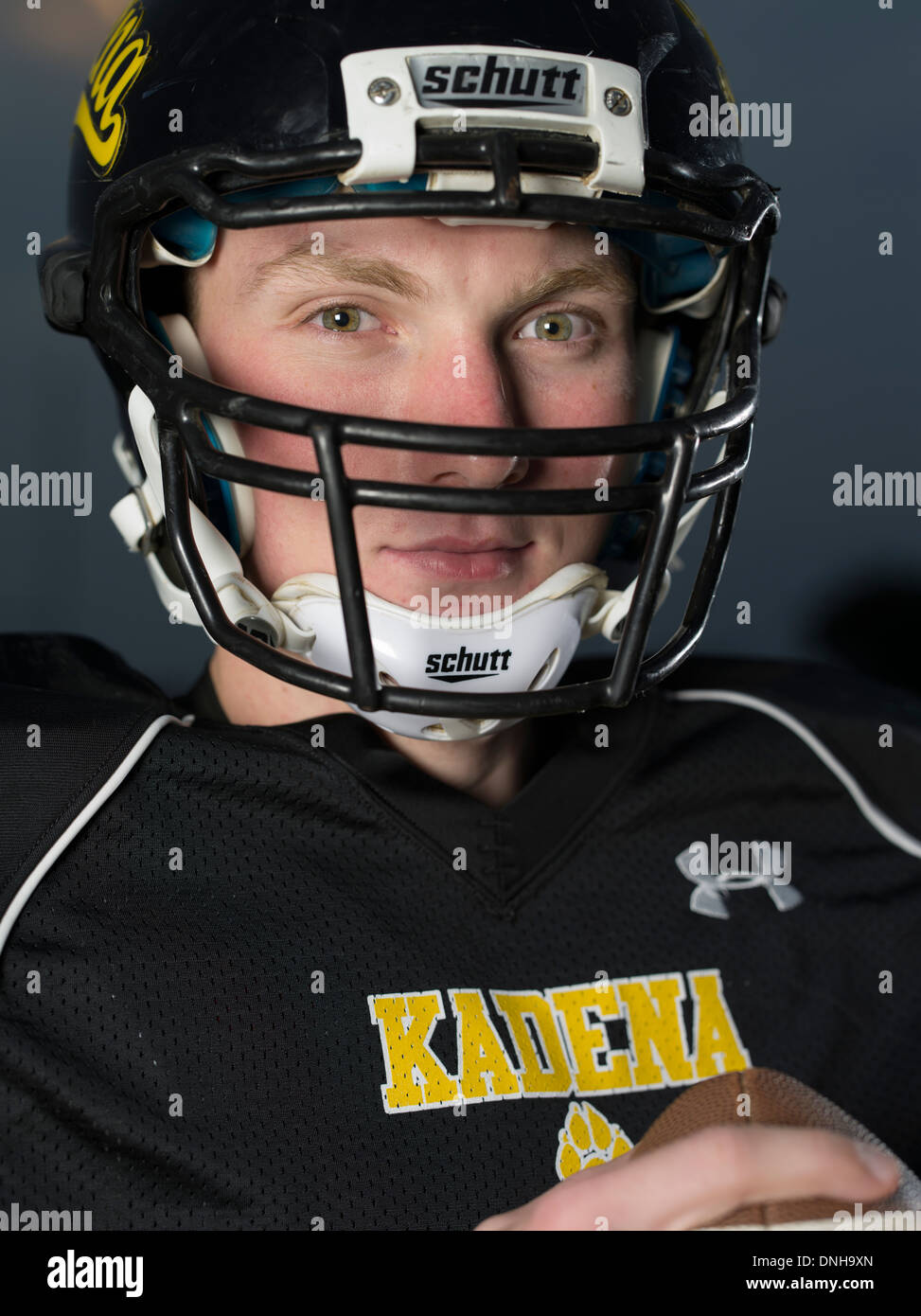 American High School Football-Spieler in Uniform mit Helm und Fußball. Stockfoto