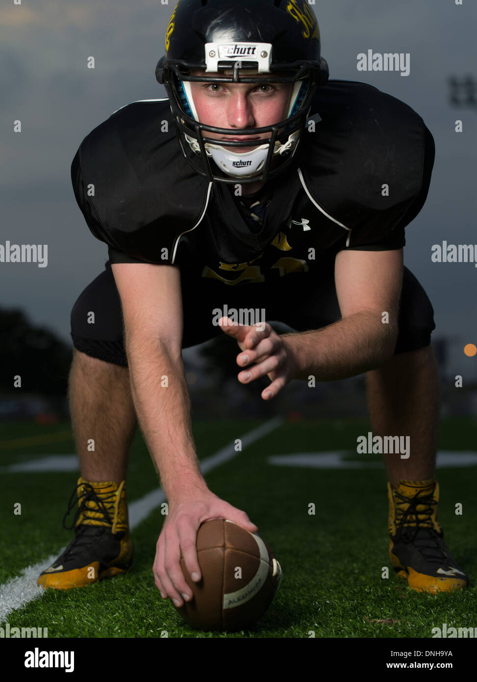 American High School Football-Spieler in Uniform mit Helm und Fußball. Stockfoto