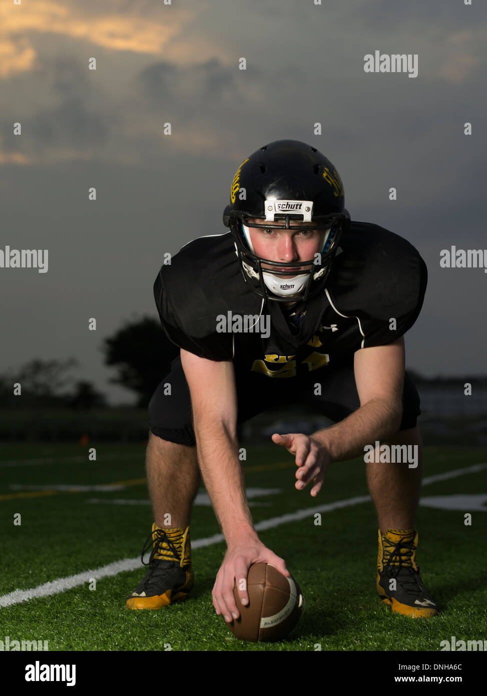 American High School Football-Spieler in Uniform mit Helm und Fußball. Stockfoto