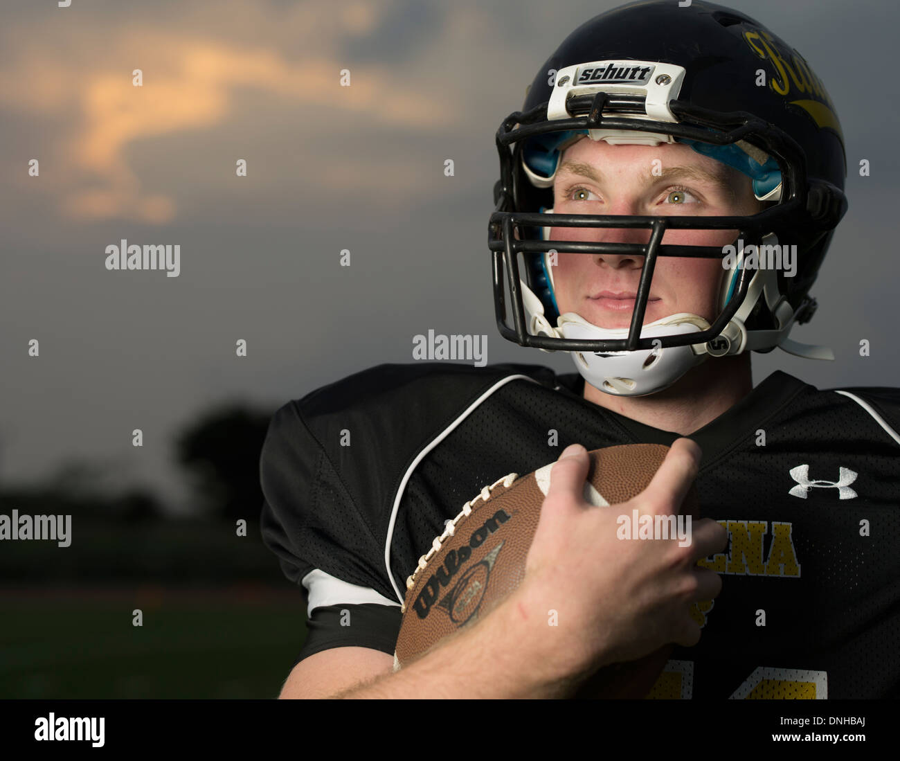 American High School Football-Spieler in Uniform mit Helm und Fußball. Stockfoto