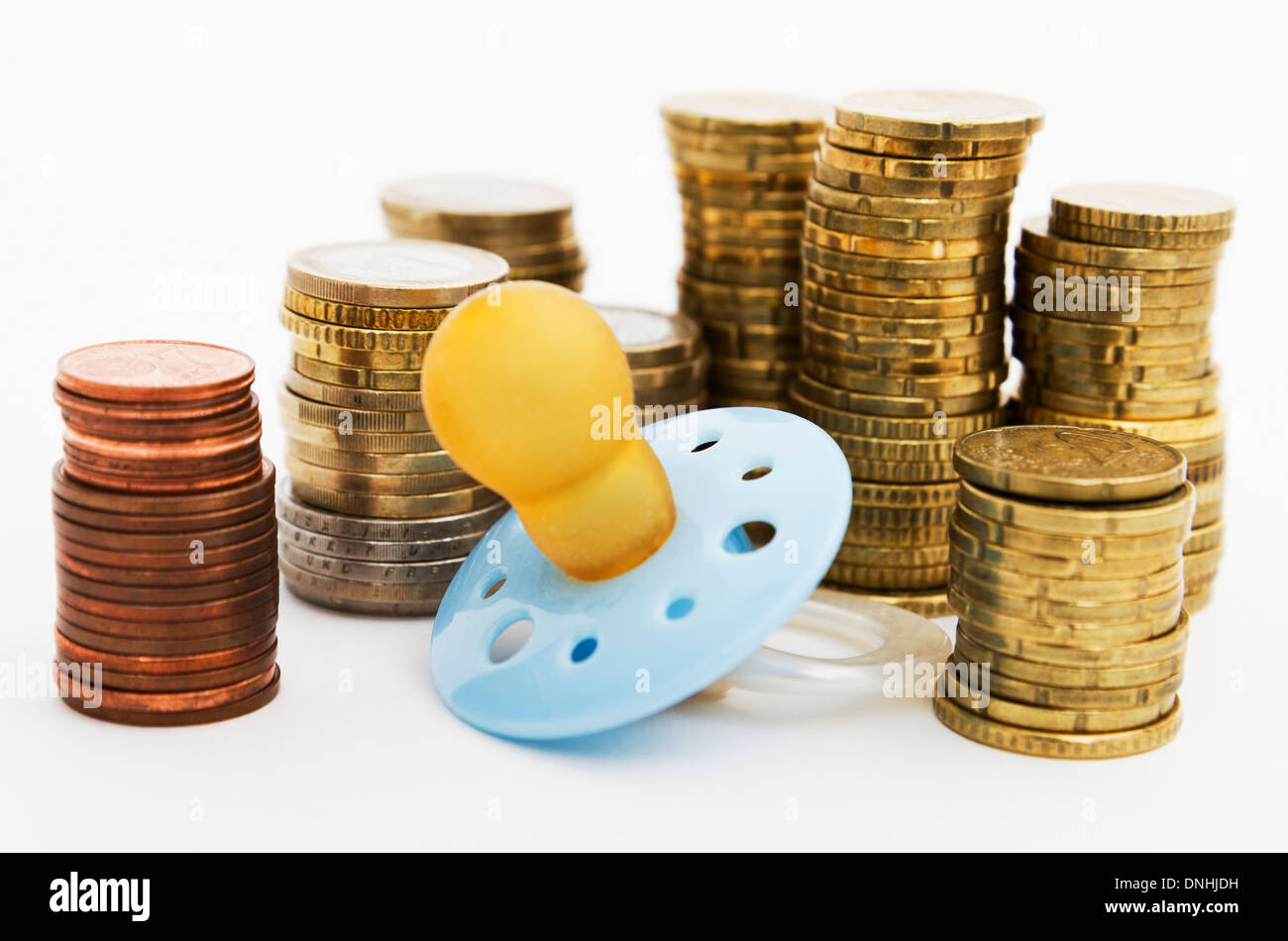 Schnuller mit harten Geldes im Hintergrund als Symbol für die Kosten der Elternschaft Stockfoto