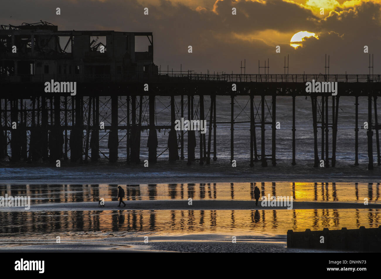 Hastings, UK. 30. Dezember 2013. Ruhepause zwischen Stürmen Sonnenuntergang hinter Regenwolken am Hastings Pier auf der Küste von East Sussex.  Die jüngste stürmische Wetter verursachte Überflutungen in ganz Großbritannien. Bildnachweis: David Burr/Alamy Live-Nachrichten Stockfoto