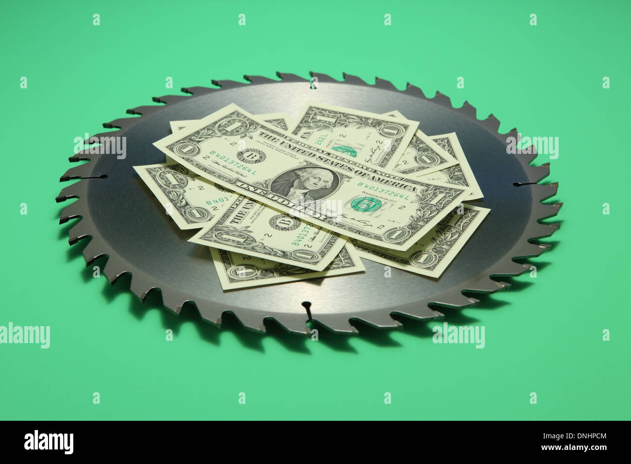 Eine scharfe Runde Metall Sägeblatt mit US-Währung auf grünem Hintergrund. Stockfoto