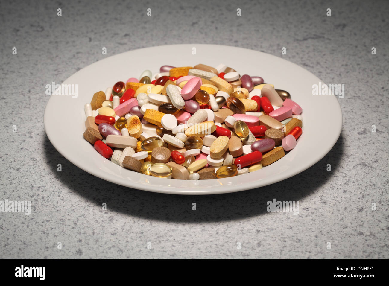 Eine Runde Platte mit gemischten Vitamin-Ergänzungen-Pillen, Tabletten und Kapseln gefüllt. Stockfoto
