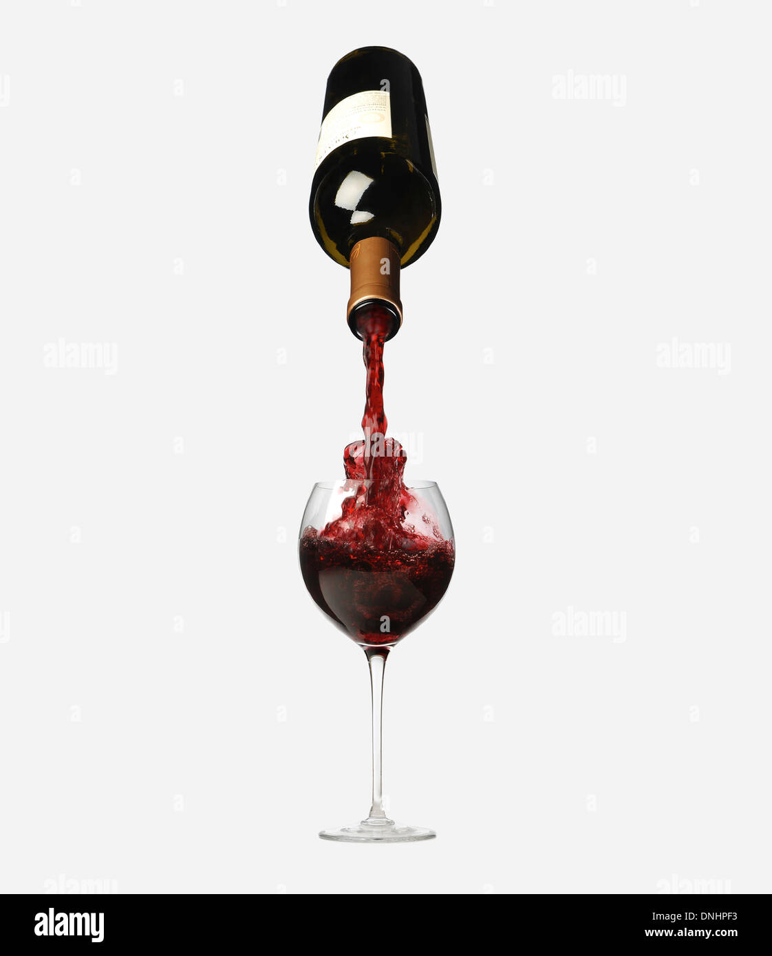 Eine Flasche Rotwein in ein Glas von oben gießen. Stockfoto