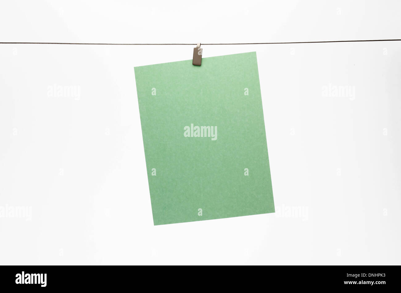 Ein leeres Blatt grün Papier mit einem Clip zu einem geraden Draht hängen. Weißem Hintergrund Stockfoto