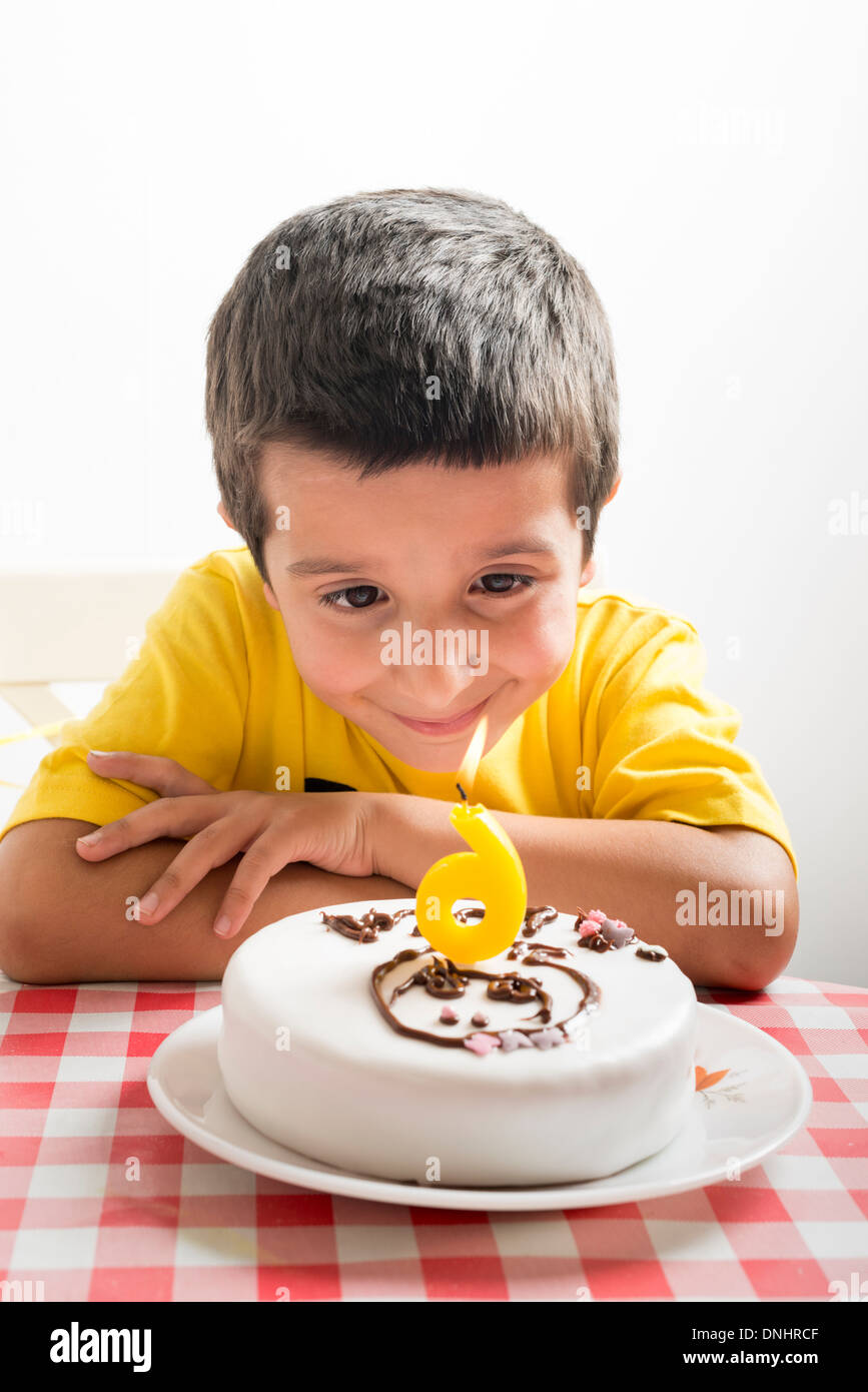 Sechs Jahre alter Junge schaut Geburtstagstorte Stockfoto