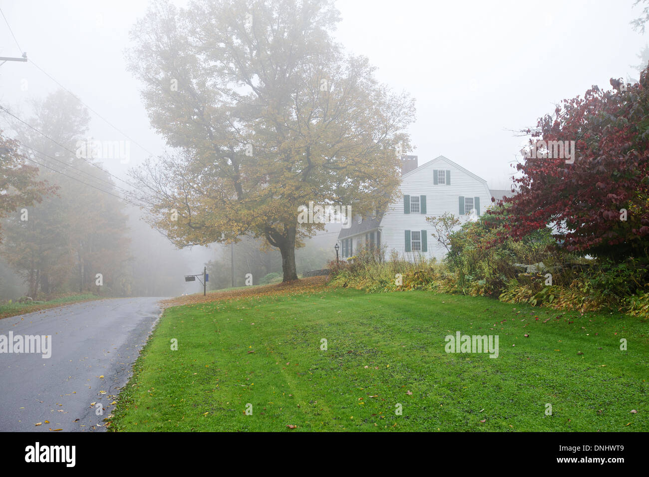 Nebligen Morgen, Herbst / Herbstfarben. Land Seitenansicht mit Holzhaus mit einem Auto auf der Straße Stockfoto