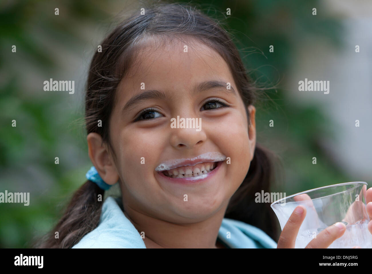 Kleines Mädchen ist aus einem Glas Milch trinken. Stockfoto