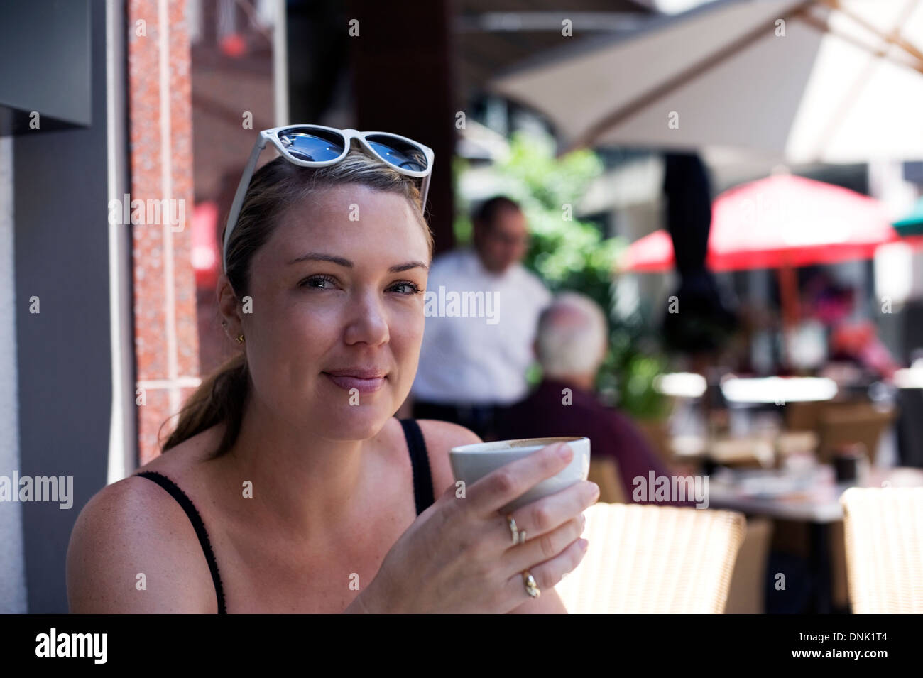 Frau in den frühen dreißiger Jahren erfreut sich einen Outdoor-Kaffee in einem der vielen Cafés von Auckland (Neuseeland) Stockfoto